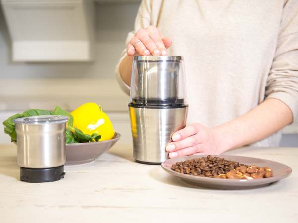 Persona che utilizza il macinacaffè elettrico VeoHome premendo il coperchio in modo sicuro.